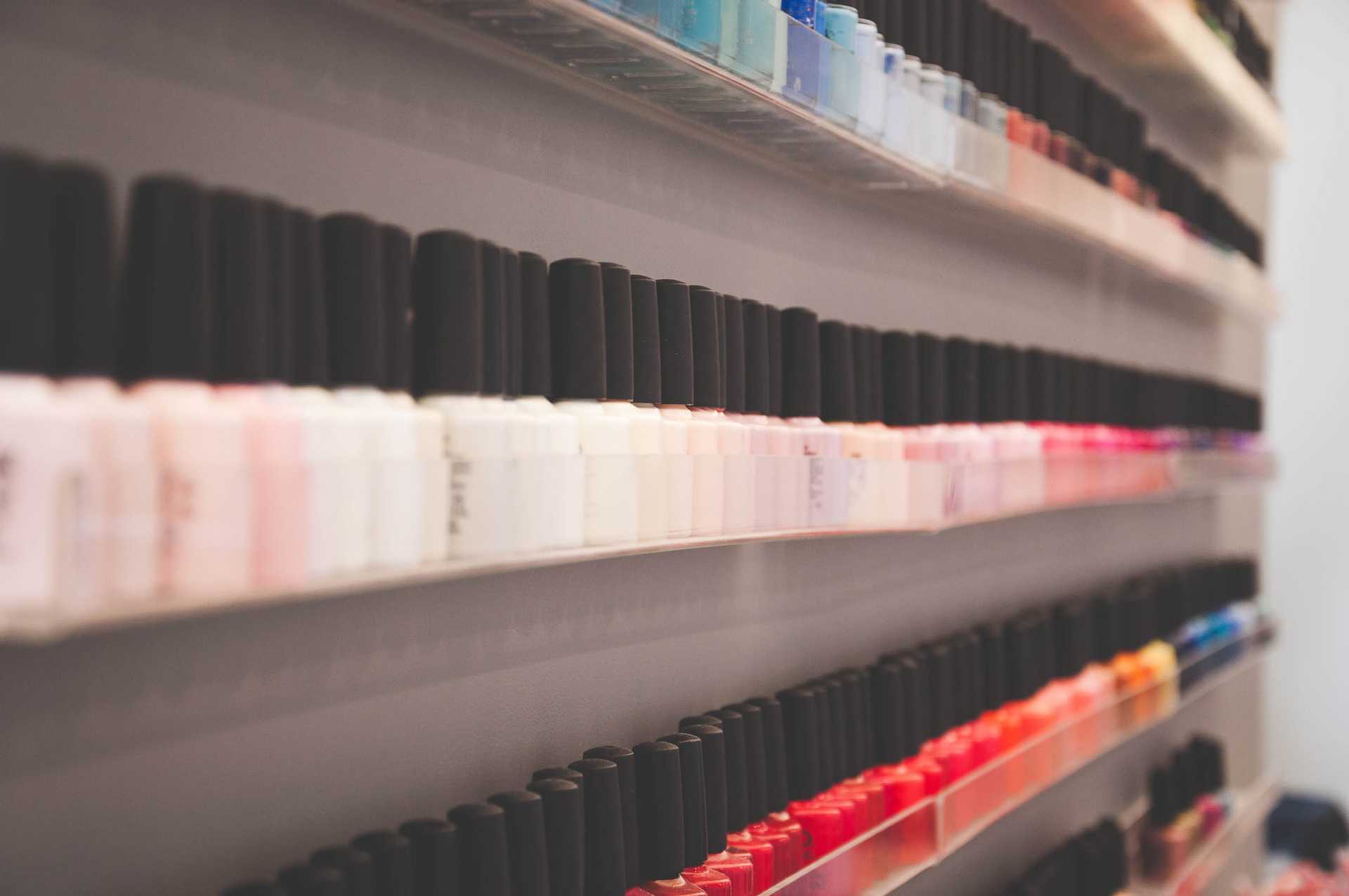 Nail polish bottles organized by color on shelves.